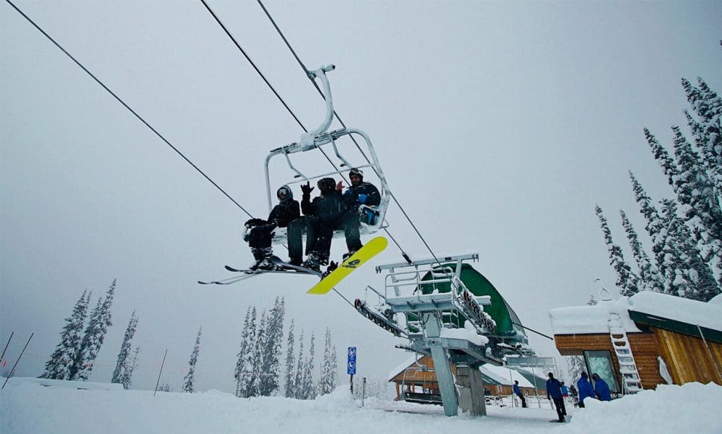 people sitting on a chairlift and waving