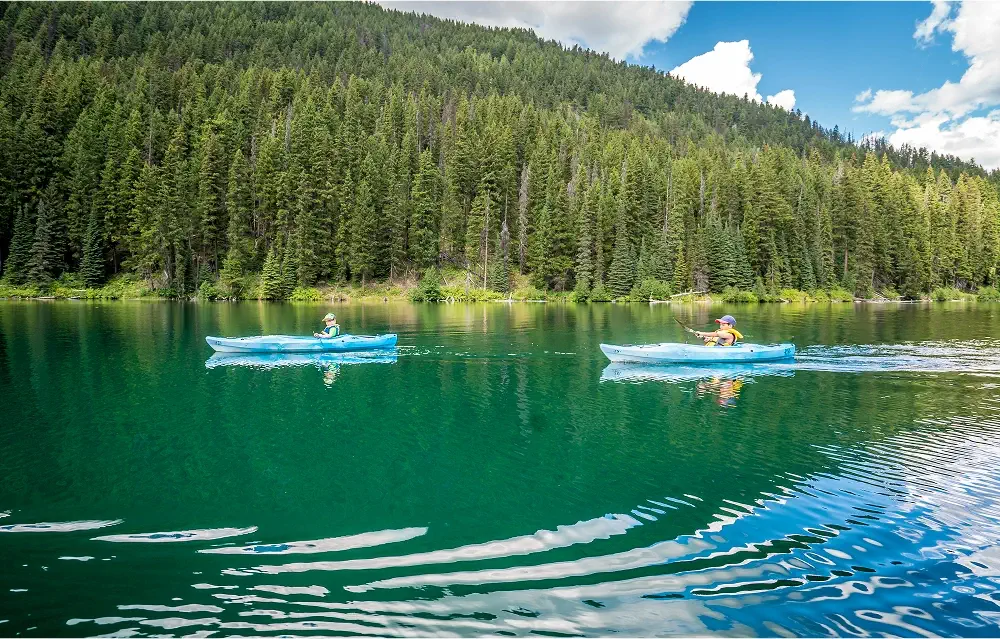 Two children kayaking on Lightning Lake in Manning Park, enjoying summer adventures.