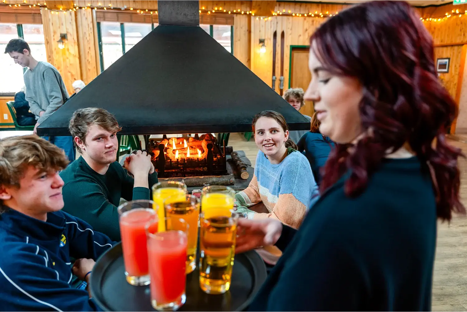 Group of guests happily receiving drinks at Pinewoods Restaurant, enjoying a lively breakfast experience.