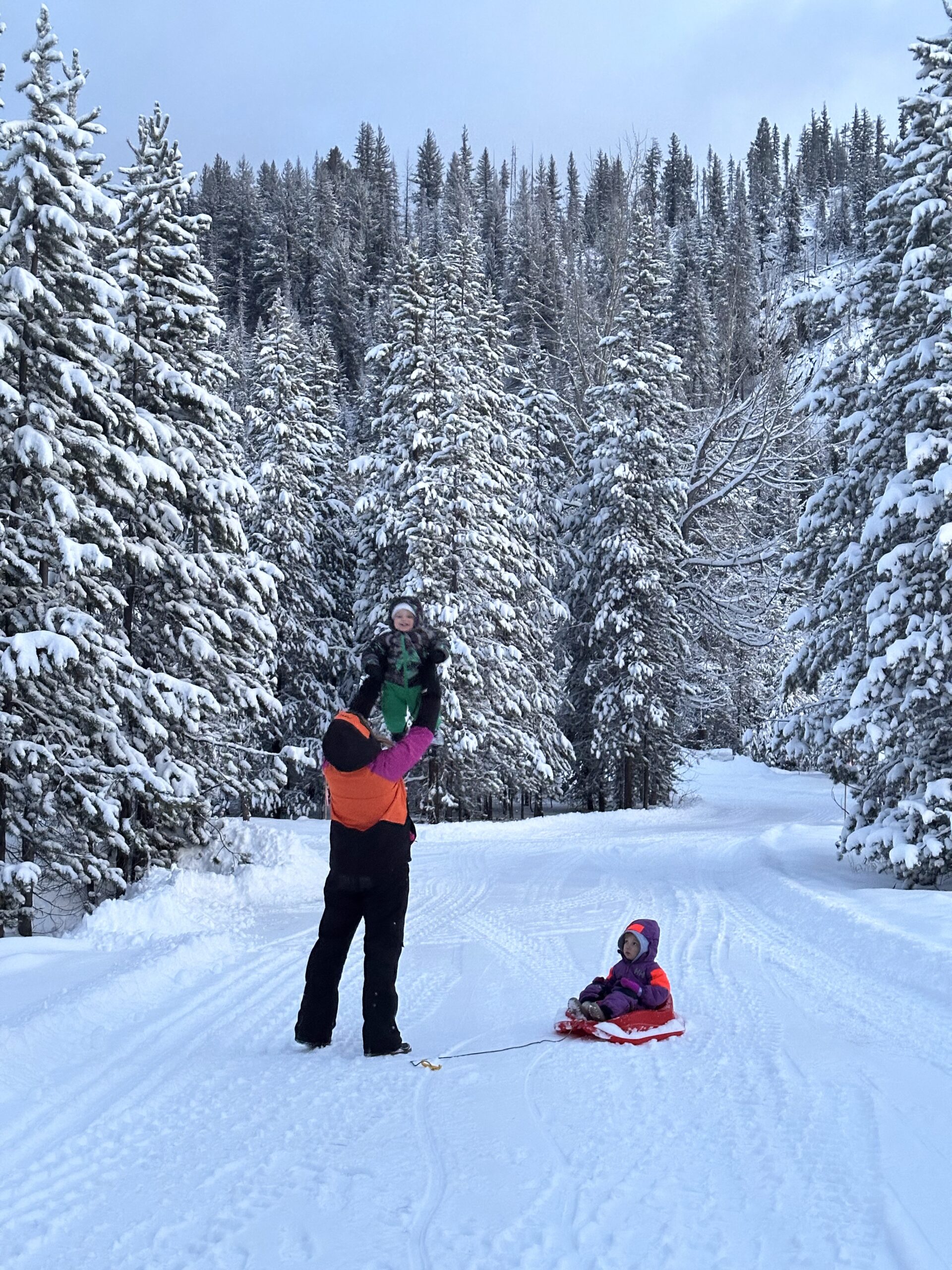 Parent playing in the snow with two children at Manning Park Resort.